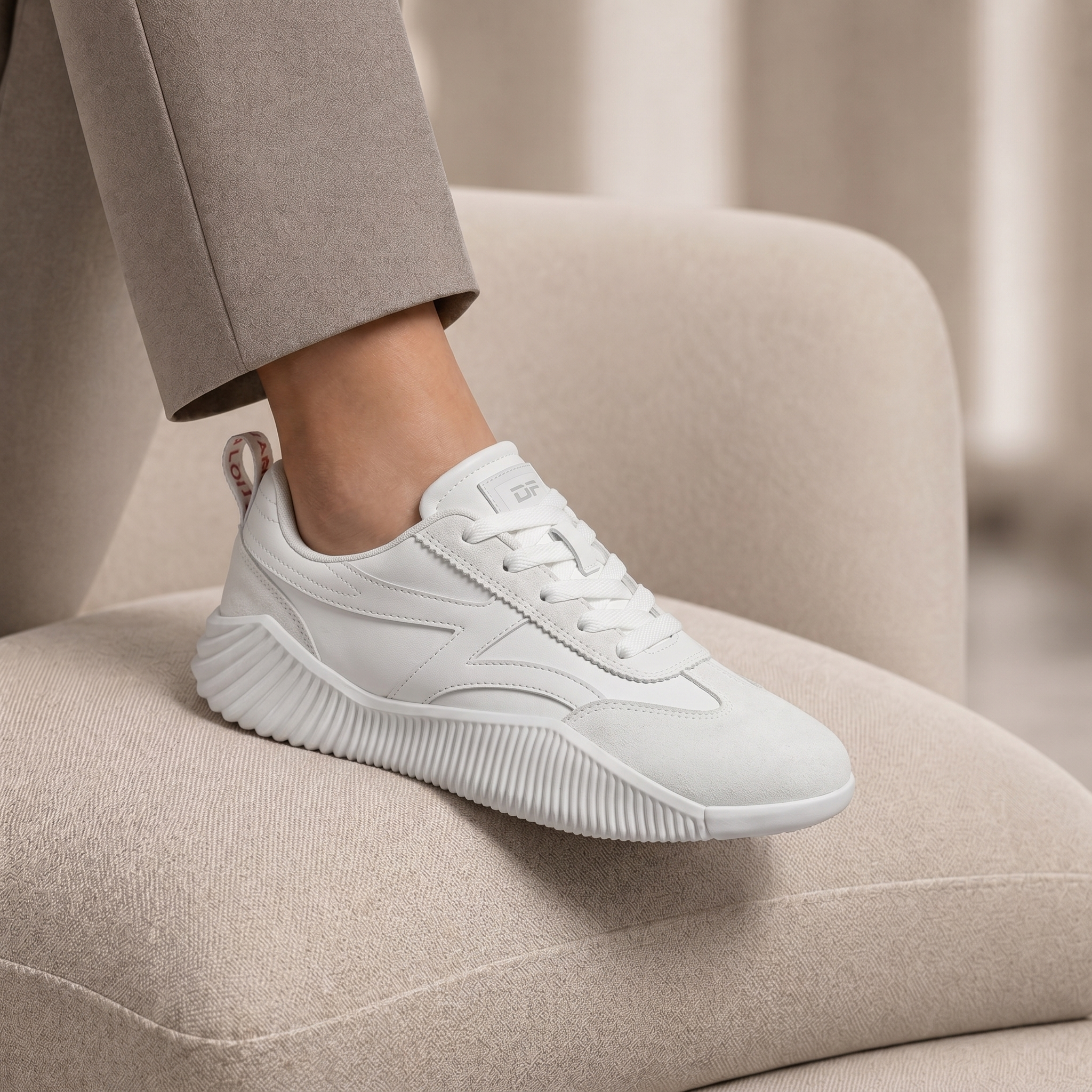 DeFlorance Cloudea 2.0 sneaker in Triple White resting on a beige armchair